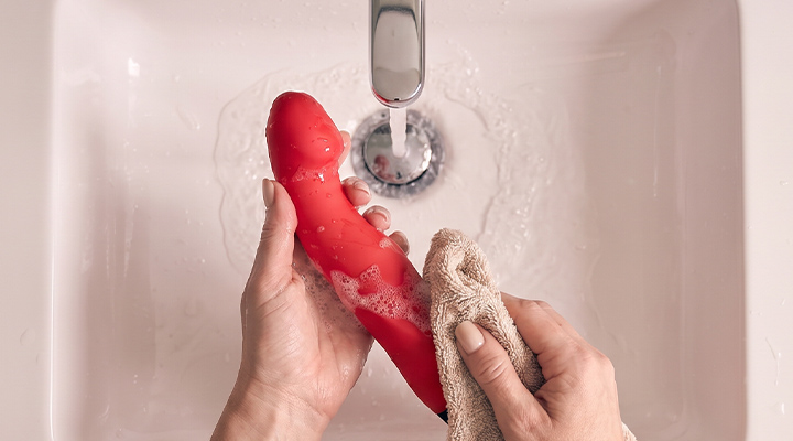 Rengøring af en vibrator med vand og klud for hygiejnisk pleje af sexlegetøj.