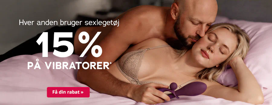 Et par ligger tæt omfavnet på en seng. Kvinden er iført lingeri og holder en lilla vibrator i hånden, mens manden kysser hende ømt på halsen og skulderen. Tekst: „Hver anden bruger sexlegetøj – 15% på vibratorer*“. Nederst er der en rød knap med hvid skrift: „Få din rabat »“.