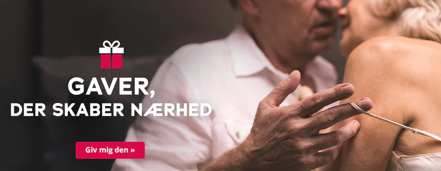 Billedet viser en reklame, hvor en kvinde og en mand står tæt sammen. Manden bærer en hvid skjorte, og kvinden bærer en lys top med tynde stropper. Deres hoveder er tæt på hinanden, og manden trækker med sin hånd kvindens tynde stropper ned over hendes skulder. Med store, hvide bogstaver står der »Gaver, der skaber nærhed«. Symbolsk er der afbildet en gave. Under billedet er der en rød knap med den hvide påskrift Kom med det » .