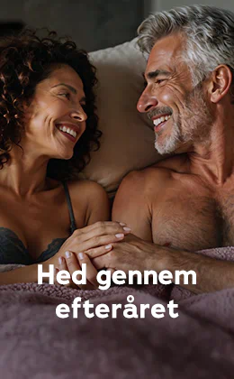Et par ligger tæt sammen i sengen og smiler til hinanden. Til venstre en kvinde i en blonde-bh med mørke krøller, til højre en mand med bar overkrop, gråt hår og skæg. Tekst: "Hed gennem efteråret." Rød knap: "Opdag lystboostere."