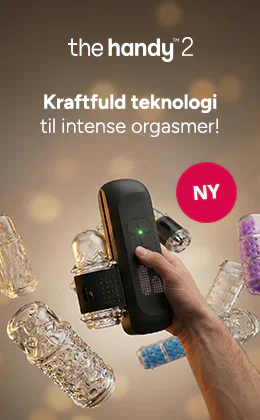 En hånd holder en sort masturbator foran en beige baggrund. I baggrunden ses flere gennemsigtige påsætningsdele. Øverst står der »the handy 2« og »Kraftfuld teknologi til kraftfulde orgasmer!«, og ved siden af er der en rød cirkel med teksten »NY«.